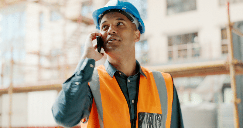 Mann, der auf der Baustelle angezogen ist und mit dem Telefon spricht - digitalen BGM