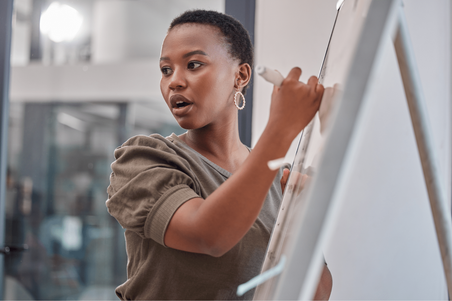 Une femme écrit sur un tableau blanc au travail - empowerment