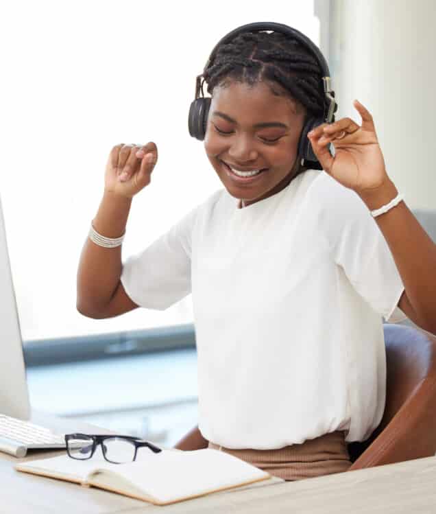 La danse, les écouteurs et la femme sur l'ordinateur, le bureau ou le lieu de travail pour la santé mentale, le bien-être et l'écoute. La personne africaine heureuse travaillant sur un ordinateur de bureau et dansant sur la musique, la célébration et le travail ou la carrière.