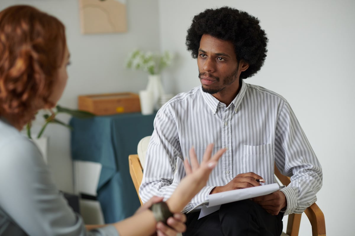 Un psychothérapeute sérieux écoute une femme qui parle de ses problèmes et prend des notes - EAP