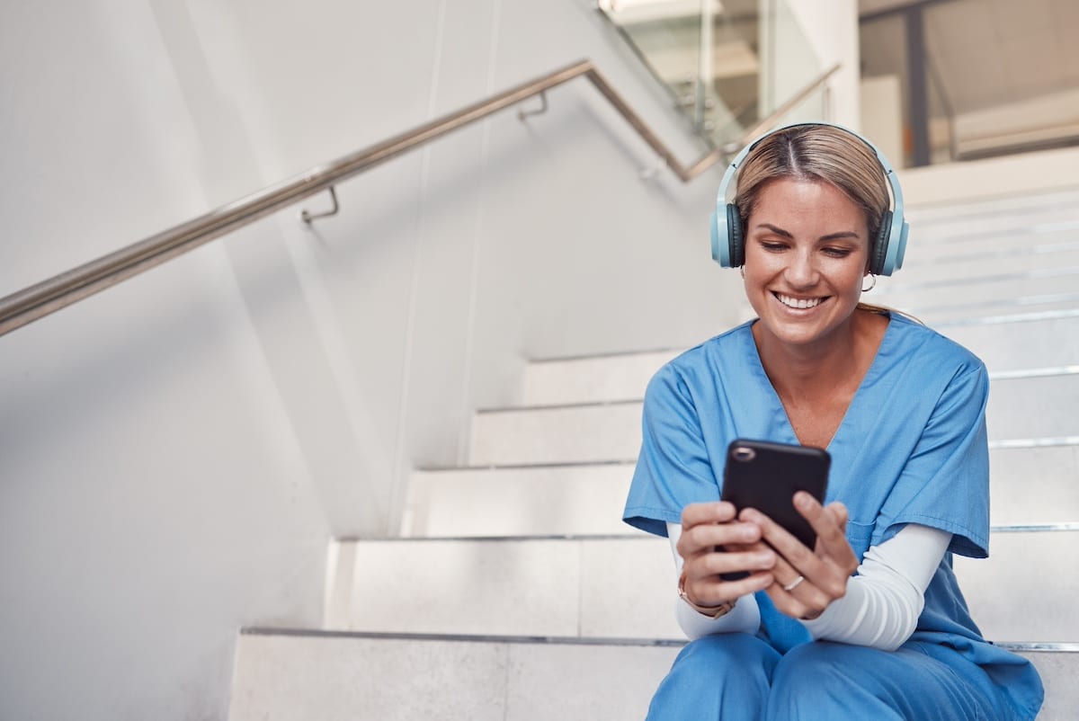 Doctor, phone and stairs for consultation, communication or video call outside hospital for health advice. Happy woman nurse smiling in healthcare with smartphone and headset for telemedicine. -