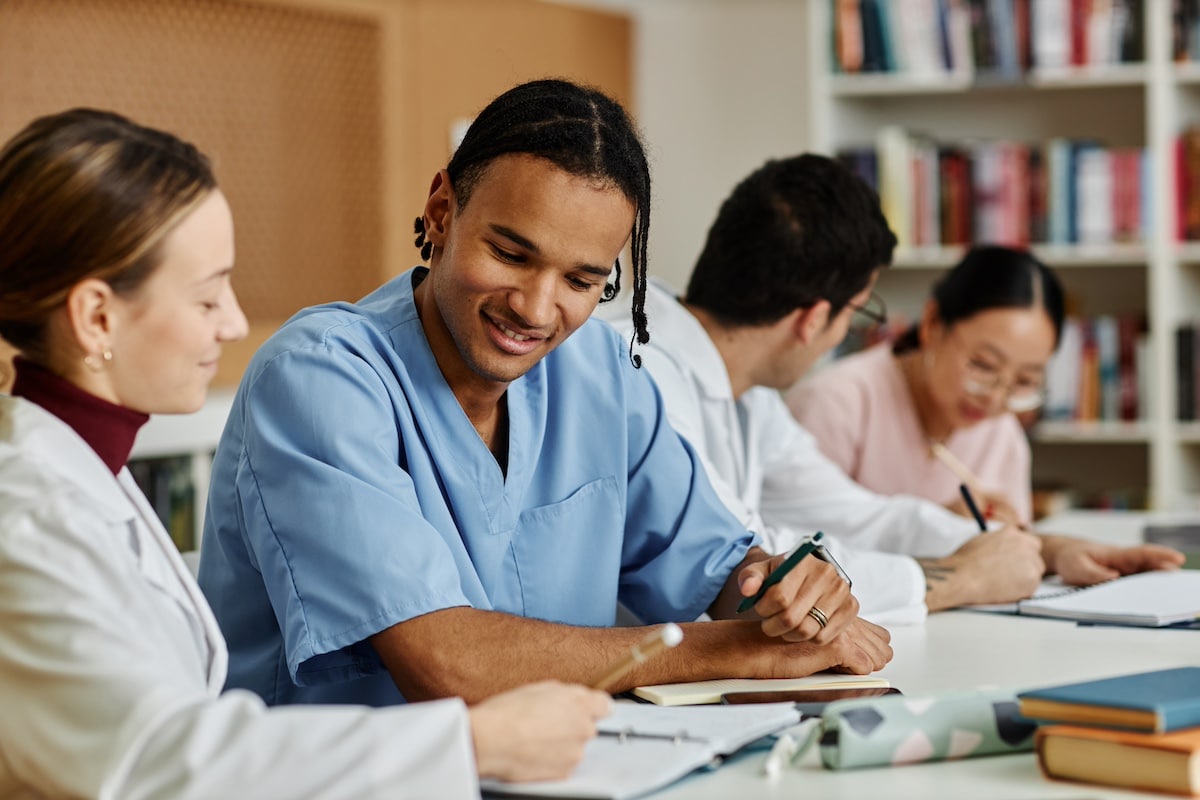 Diverse group of young medical professionals at table during meeting or seminar - Empowering caregivers