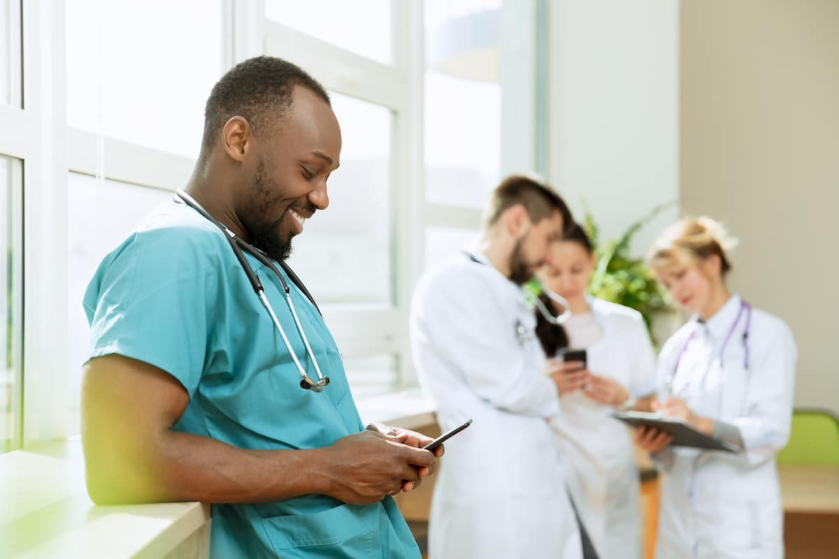 Healthcare people group. Professional african american male doctor with phone posing at hospital office or clinic. Medical technology research institute and doctor staff service concept. Happy smiling models. -