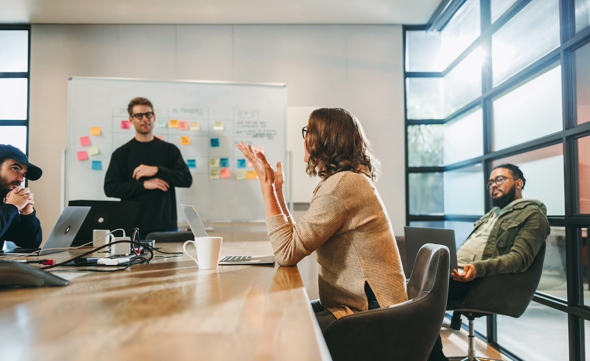 Diverse professionals engage in a collaborative discussion. Seated in a well-lit boardroom, they brainstorm project management and software development. Focused on teamwork, they exchange ideas and discuss the framework. -