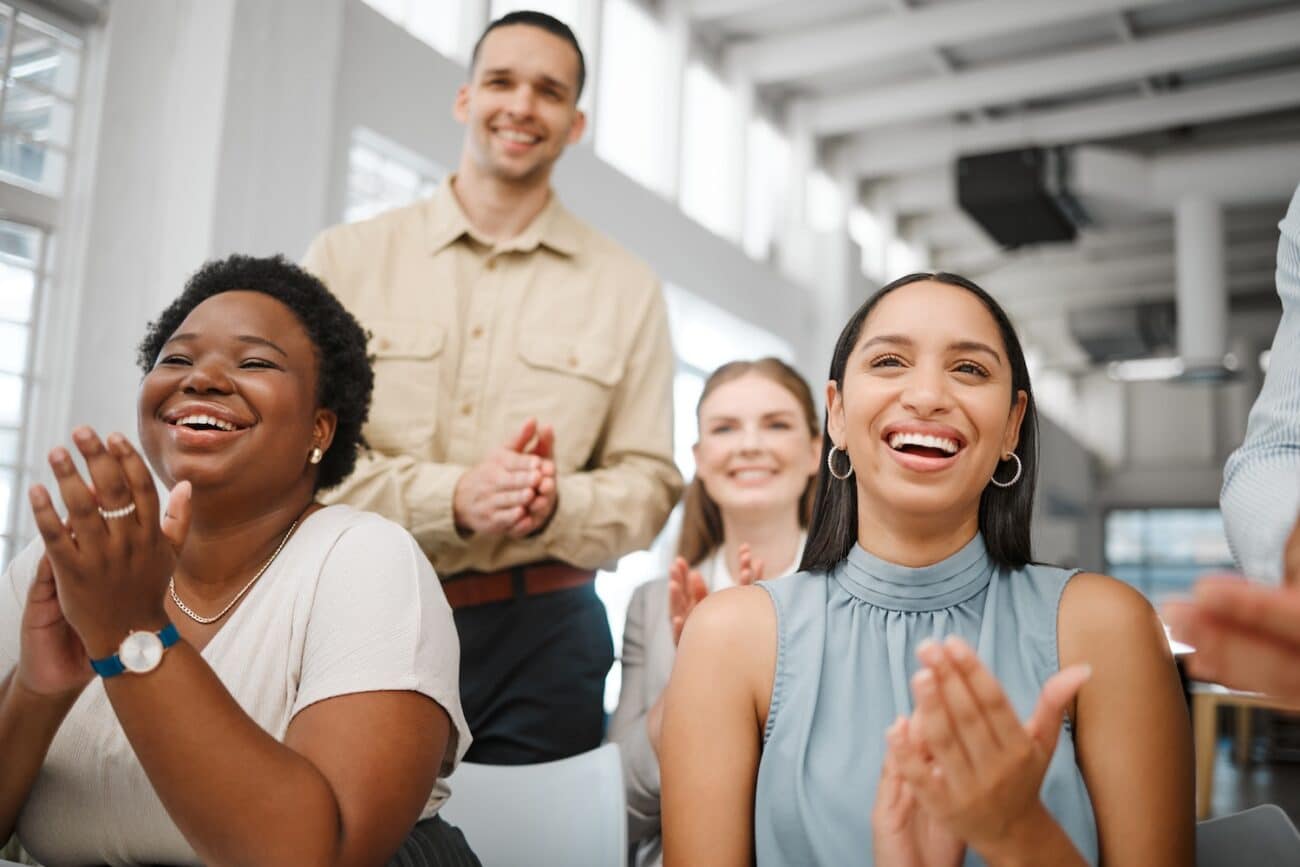 Clapping, celebrating and excited after training presentation, office meeting or education workshop for creative group. Diverse, cheering or motivated colleagues smiling with growth mindset or vision.