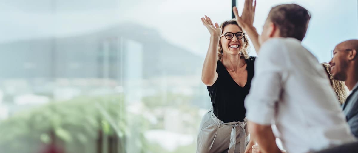 Businesswoman giving a high five to male colleague in meeting. Business professionals high five during a meeting in boardroom. -