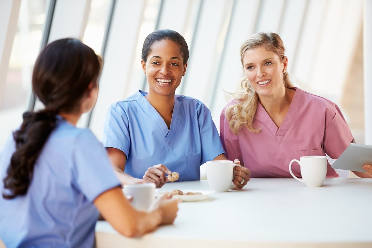 Group Of Nurses Chatting In Modern Hospital Canteen -