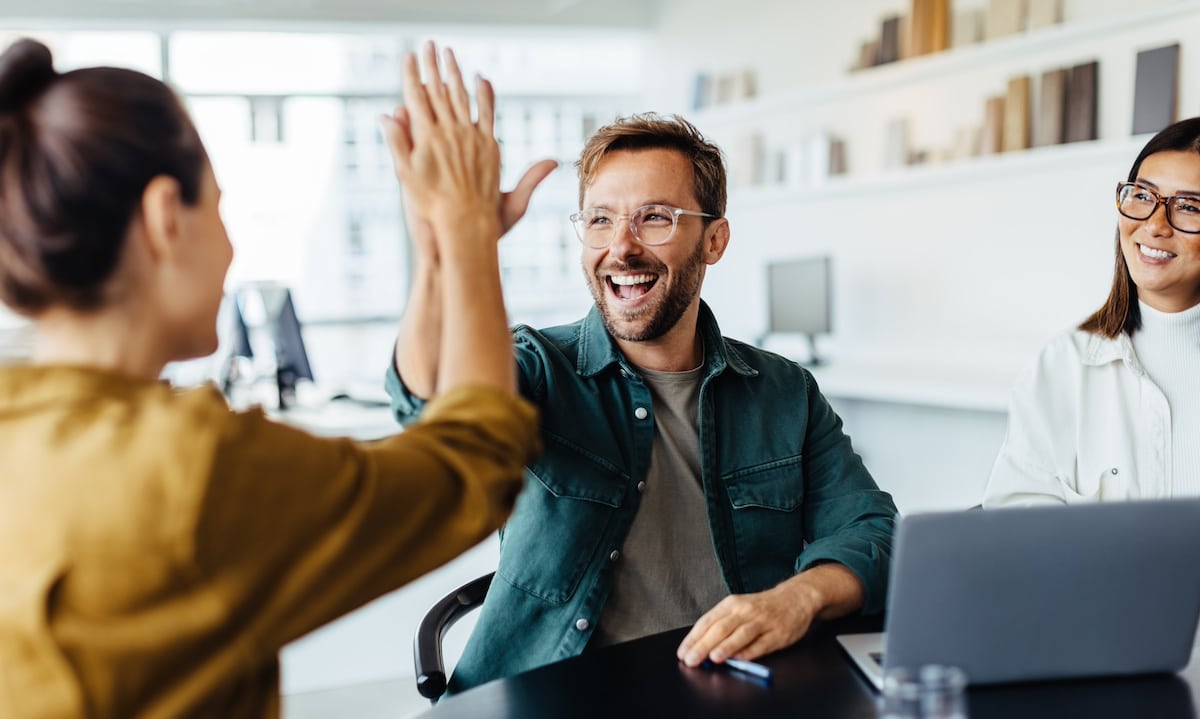 Successful business people giving each other a high five in a meeting. Two young business professionals celebrating teamwork in an office. - health program