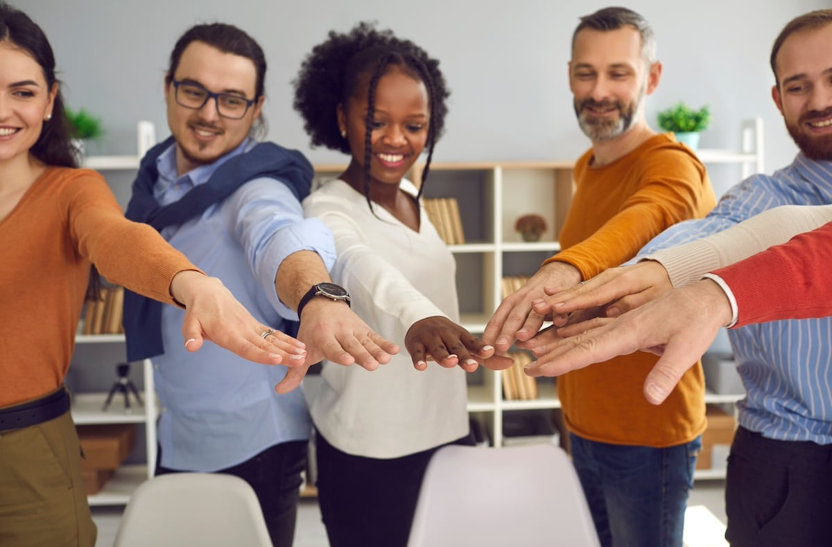 Humanism and social responsibility, business training and corporate coaching session concept. Group of diverse multiracial people different age holding hands joining together front view shot -