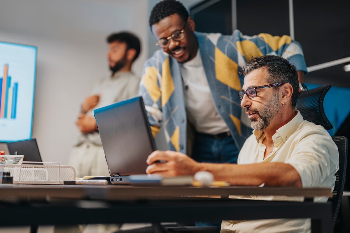 Multicultural business team collaborates in a board meeting. Professionals work together using technology to develop projects and achieve profit growth in a supportive and cooperative environment. -