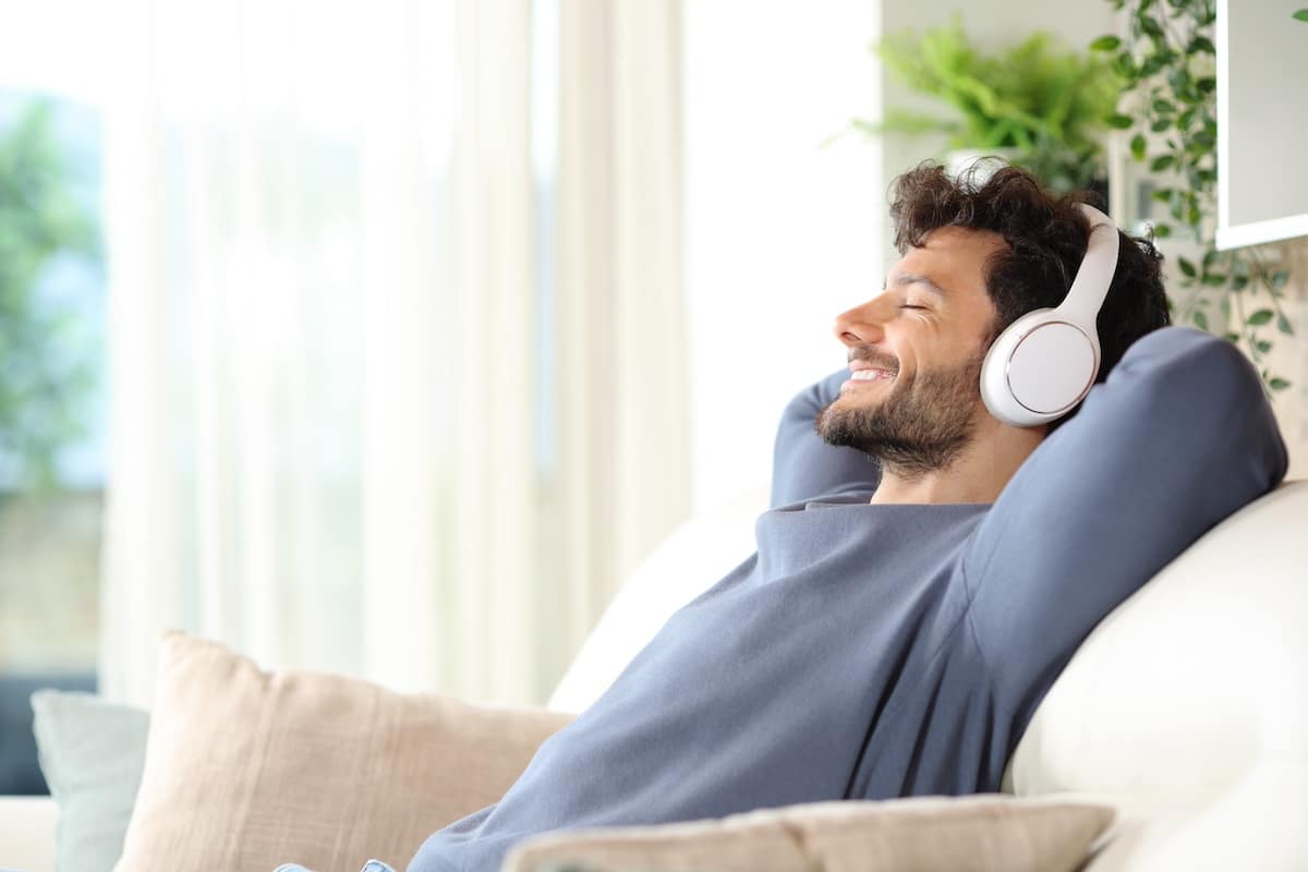 Happy man listening music and relaxing on a couch - employee wellbeing