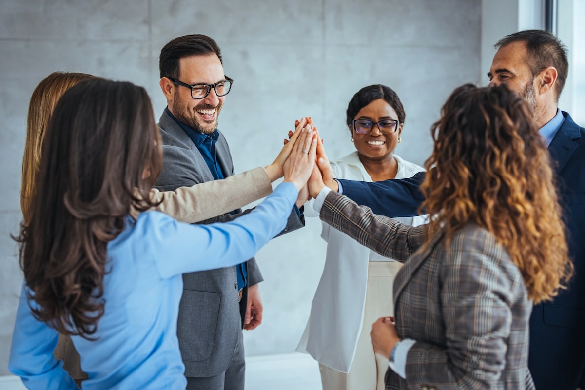 Diverse Team Celebrating Success With High Five in Office - employee motivation