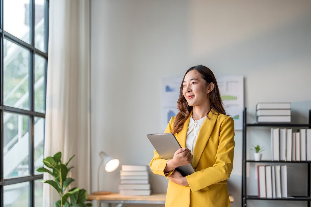 Young asian businesswoman is smiling while holding a laptop in her office - employee retention